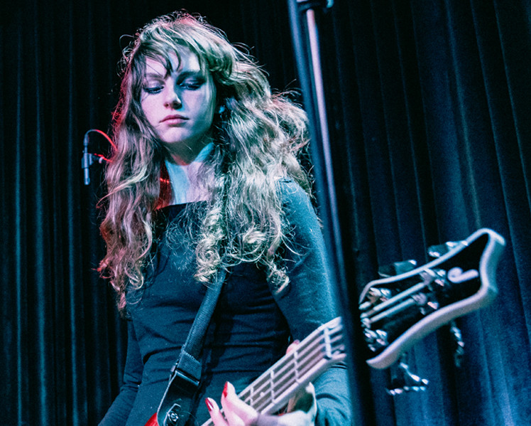 Girl in rock band plays bass on stage